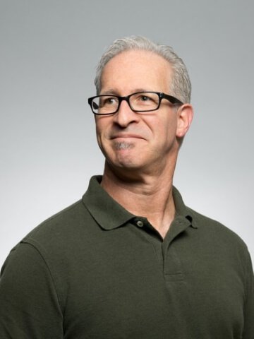 Jonathan Doe, Headmaster of Campions School, in a studio portrait wearing glasses and a dark green polo shirt, representing trusted guidance for students seeking MBBS abroad consultancy and MBBS admission abroad