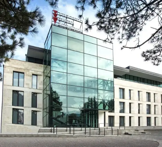 East European University modern glass-front campus building in Tbilisi, Georgia surrounded by trees, highlighting one of the top universities in Georgia for MBBS for Indian students.